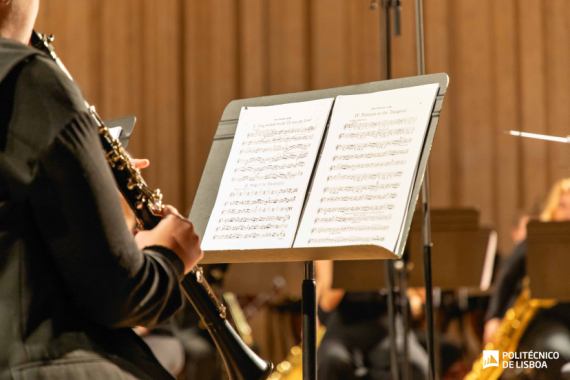 Músico a tocar clarinete em palco, lendo uma partitura num suporte, durante um ensaio ou concerto de orquestra
