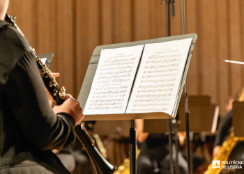 Músico a tocar clarinete em palco, lendo uma partitura num suporte, durante um ensaio ou concerto de orquestra